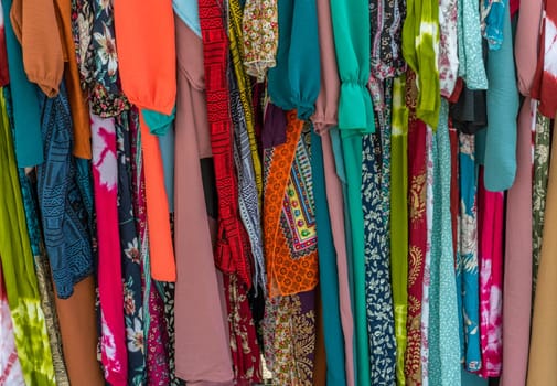 used colorful clothing hanging on a rack at a flea market