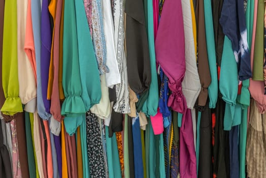 used colorful clothing hanging on a rack at a flea market