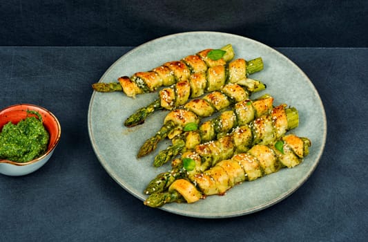 Delicious bread sticks stuffed with asparagus and pesto sauce on a plate. Top view.