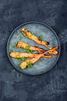 Tasty shrimp barbecue with herbs fried on wooden sticks. Prawns skewers. Space for text