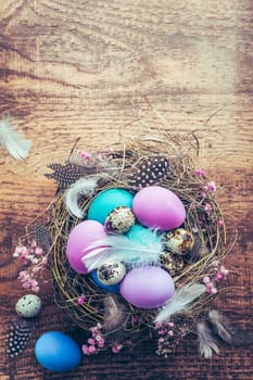 Happy Easter - nest with Easter eggs on wooden background with copy space