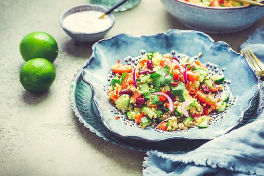 Healthy quinoa black bean salad with fresh tomatoes, cucumbers, onion and cilantro