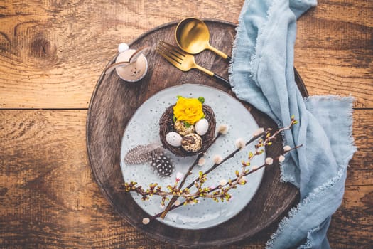 Easter table setting with spring flowers and cutlery on wooden table. Spring Easter Holiday Table