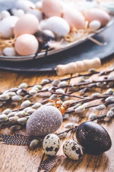 Easter eggs with pussy-willow branch on wooden kitchen table