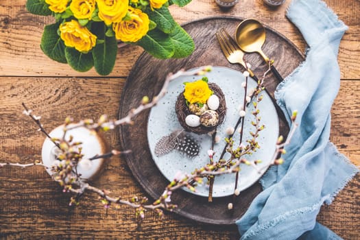 Easter table setting with spring flowers and cutlery on wooden table. Spring Easter Holiday Table
