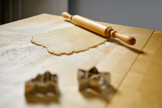 Flat ginger dough on the kitchen table and rolling pin (selective focus photo)