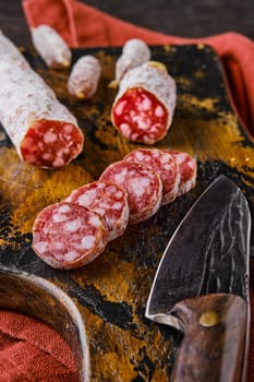 Fermented salami sausages on wooden cutting board cut on slices, closeup view