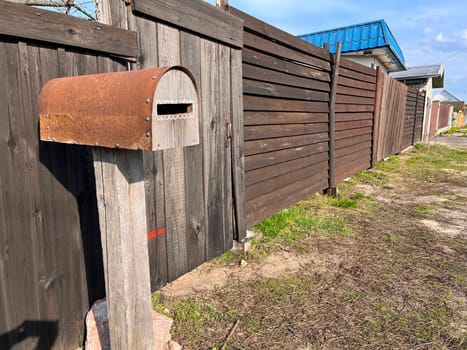 wooden new unpainted fence near the house in the village and wooden original mailbox