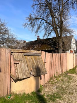 wooden old painted fence near the house in the village and a closed well