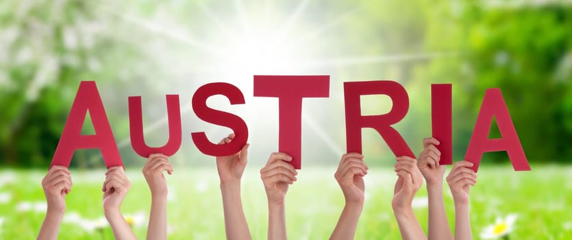 People Or Persons Hands Building English Word Austria. Sunny Green Grass Meadow As Background.