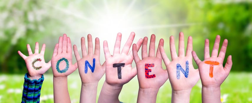 Children Hands Building Colorful English Word Content. Sunny Green Grass Meadow As Background.