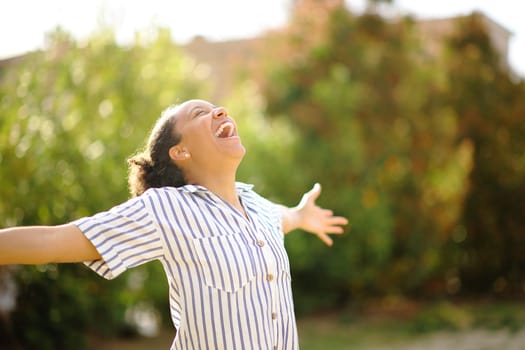 Excited black woman spreading and screaming in a park