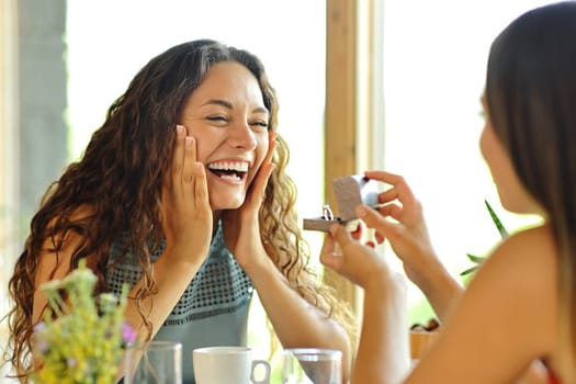 Happy lesbian couple asking for marriage in a restaurant