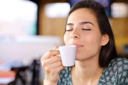 Relaxed woman smelling coffee cup in a restaurant