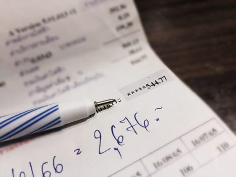 Bill and pen on dark wooden table, Bill for income and expenditure in still life tone