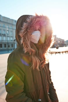 Girl wearing the face mask to avoid virus infection and to prevent the spread of disease. Young woman walking in city centre. Virus infection protection. Real people, authentic situations