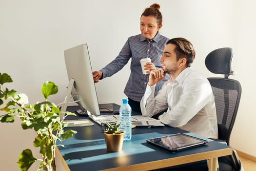 Two business people discussing financial data on computer. Businesswoman working with male colleague in office. People entrepreneurs working with charts and tables on screen. Two people working together. Workmates talking about project