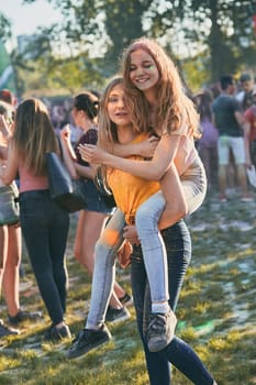 Portrait of happy smiling young girls with colorful paints on faces and clothes. Two friends spending time on holi color festival