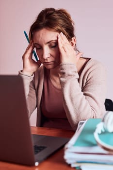 Woman focused on her work working hard doing her job remotely on laptop from home. Woman sitting at desk in front of computer looking at screen. Concept of remote working