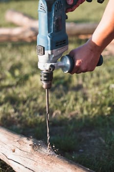 Man drilling hole in timber while working in garden