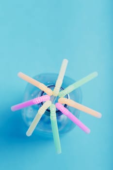 Plastic bottle with colorful straws over blue background. Collecting plastic waste to recycling. Concept of plastic pollution and too many plastic waste. Copy space at the top