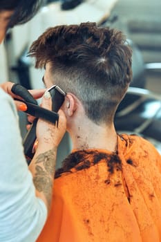 Hairdresser haircutting styling young man's hair in barbershop. Young woman working as a hairdresser in hair salon. Real people, authentic situations