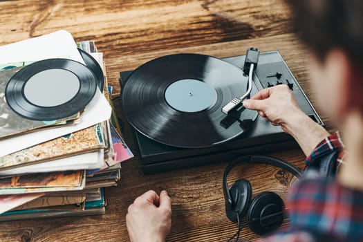 Man listening to music from vinyl record. Playing music from analog disk on turntable player. Enjoying music from old collection. Relaxing at home. Retro and vintage. Music passion