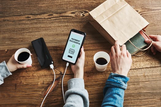 Online shopping. Buying online. Ordering product in online shop using smartphone. Order confirmation on screen. Payment successful. Online banking. People paying online. Paying for online shopping while charging mobile phone from powerbank in coffee shop