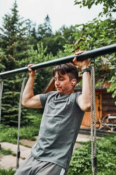 Young man doing pull-ups on pull-up horizontal bar during his calisthenics workout on a camping during his summer vacation trip