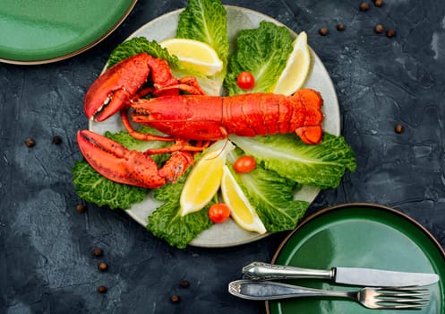 Cooked lobster with greens and lemon on a plate. Seafood. Top view.