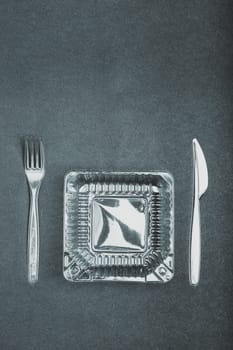 Plastic box and cutlery over dark background. Collecting plastic waste to recycling. Concept of plastic pollution and too many plastic waste. Copy space at the top