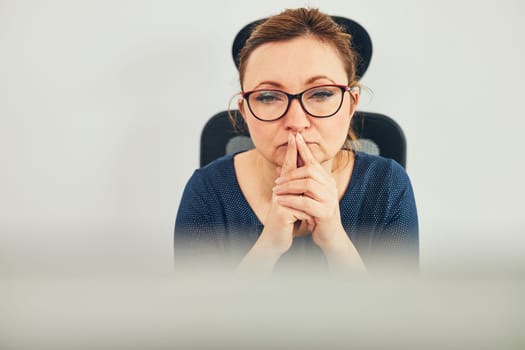 Woman entrepreneur focused on solving difficult work. Confused businesswoman thinking hard looking at computer screen sitting at her desk in office