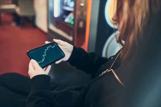 Person investing trading on stock cryptocurrency market using investing application on smartphone. Stock market investment in hand. Trader holding mobile phone looking at candle chart