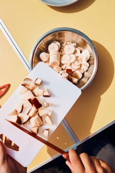 Man preparing healthy breakfast with fruits and oat flakes outdoors on camping. Close up of male hands cutting apples and bananas for breakfast. Camp life