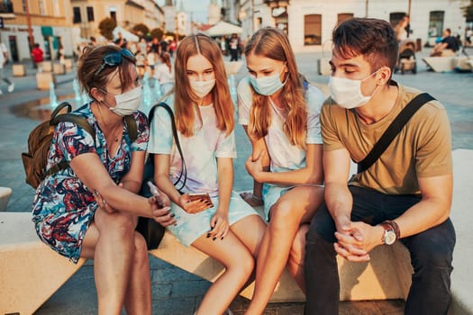Family spending time together sitting in the city center. Girls wearing the face masks to avoid virus infection and to prevent the spread of disease in time of coronavirus
