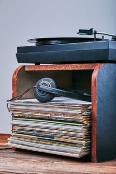 Stack of black vinyl records, turntable vinyl player and headphones. Classic stereo set. Candid people, real moments, authentic situations