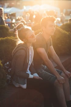 Couple of friends, teenage girl and boy,  having fun together, sitting in center of town, spending time together