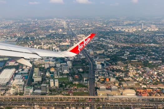 Bangkok Thailand - March 28, 2019: AirAsia (a popular low-cost airline)'s aircraft wing just took off from Don Mueang Airport. The ground image shows the city of Bangkok, the capital of Thailand.