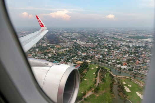 Bangkok Thailand - March 30, 2019:The image depicts the view outside the window showing the wing and engine of an AirAsia low-cost airline aircraft during landing at Don Mueang International Airport.