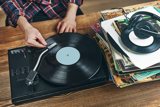 Man listening to music from vinyl record. Playing music from analog disk on turntable player. Enjoying music from old collection. Relaxing at home. Retro and vintage. Music passion