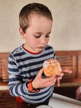 Boy enjoying eating sweet tasty cupcake that you she made herself at home