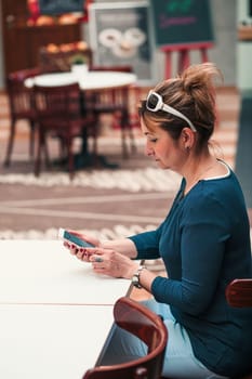 Young woman using mobile phone sitting by a table in cafe