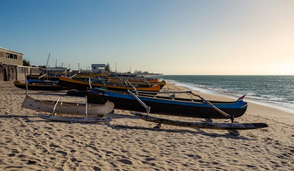 An empty wooden traditional fishing boat on the shore, waiting for the next catch of the day in Madagascar. Traditional wooden fishing boats on the tropical beach of Anakao, Toliara, Madagascar.