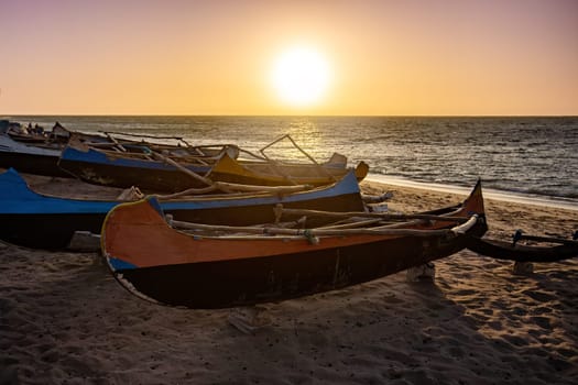 An empty wooden traditional fishing boat on the shore of Anakao beach, waiting for the next catch of the day in Madagascar. Sunset over sea on the tropical beach of Anakao, Toliara, Madagascar..