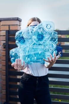 Young woman throwing out empty used plastic water bottles into trash bin. Collecting plastic waste to recycling. Concept of plastic pollution and too many plastic waste. Environmental issue