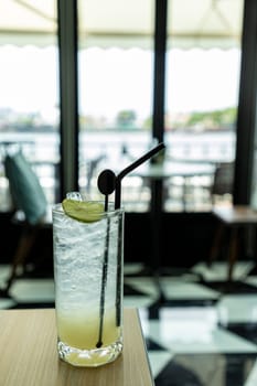 Lemonade looks delicious, cool and refreshing in a classic style cafe by the river. The atmosphere is pleasant to sit and listen to chill music for a long time. It is a vertical picture.