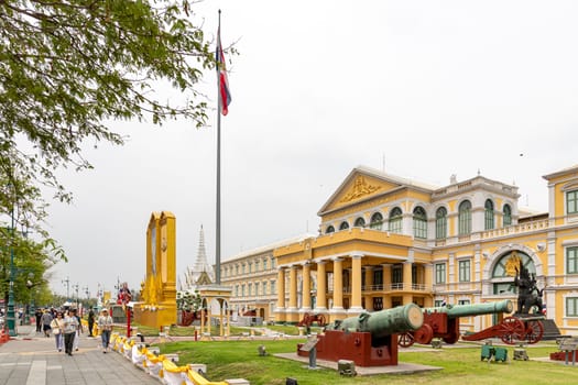 Bangkok,Thailand- April16, 2023: Building of the Ministry of Defense of Thailand​ It is a European-style building, yellow, with a white line. In front of the building there are 40 antique real cannons