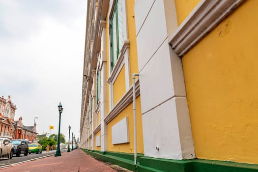 Bangkok,Thailand - April 16, 2023: The yellow building contrasts with the white stripes and has light green windows of Thailand's Ministry of Defense. A popular spot for tourists to take pictures.