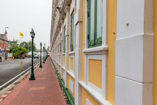 Bangkok,Thailand - April 16, 2023: The yellow building contrasts with the white stripes and has light green windows of Thailand's Ministry of Defense. A popular spot for tourists to take pictures.
