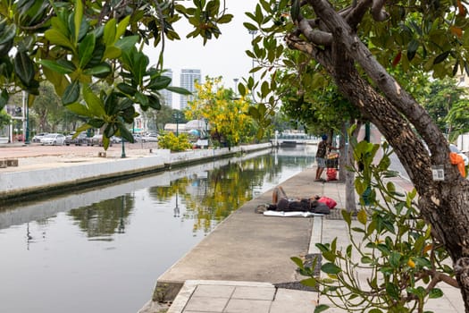 Bangkok,Thailand - April 16, 2023: If coming to Bangkok, you will be able to see homeless people resting on the sidewalks along the Khlong Lot. in front of Rattanakosin Hotel, Ratchadamnoen Road